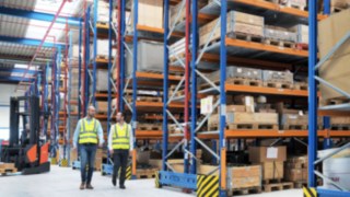 Mitarbeiter von Yanmar Compact Equipment Europe laufen durch das neue Logistikzentrum, das von Linde Material Handling geplant wurde. 