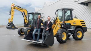 Dominik Haag und Markus Köhler von Yanmar Compact Equipment Europe Dominik Haag und Markus Köhler von Yanmar Compact Equipment Europe stehen in der Schaufel eines Fahrzeugs.